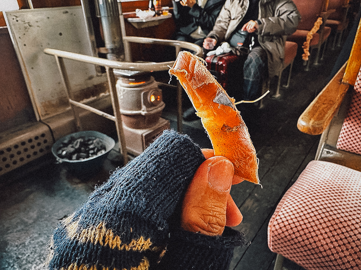 Holding up a piece of dried squid