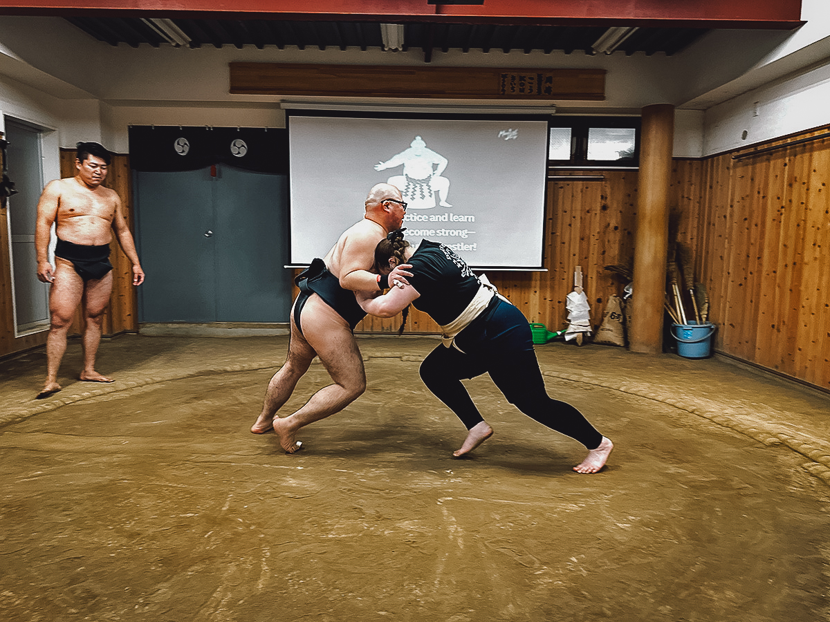 Sumo wrestler grappling with tourist